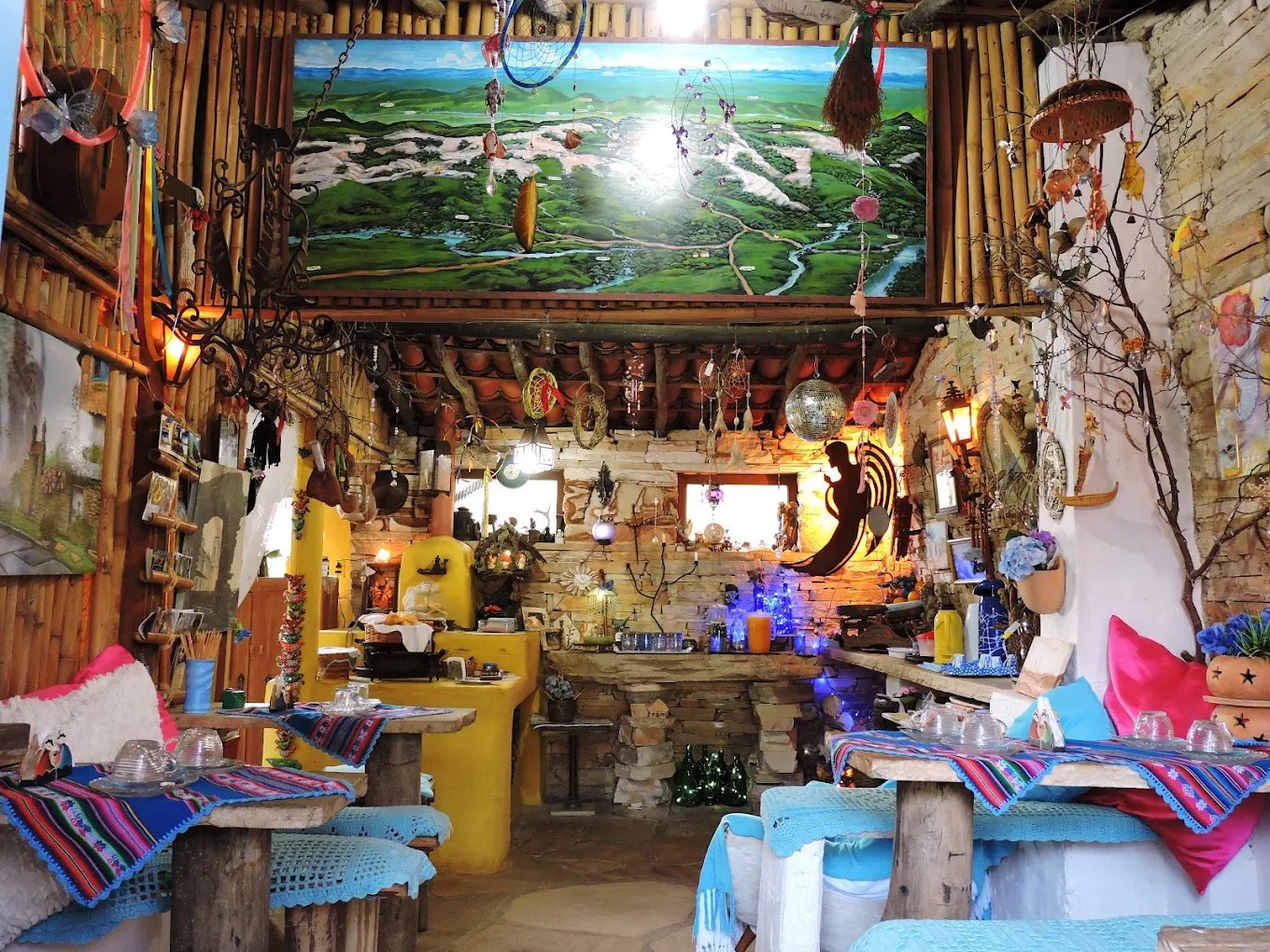 Salão do café com teto de telhas e bambu, mural do vale, luzes e objetos artesanais